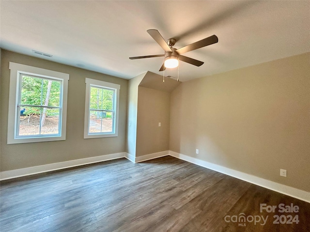 empty room featuring dark wood-style floors, visible vents, ceiling fan, and baseboards