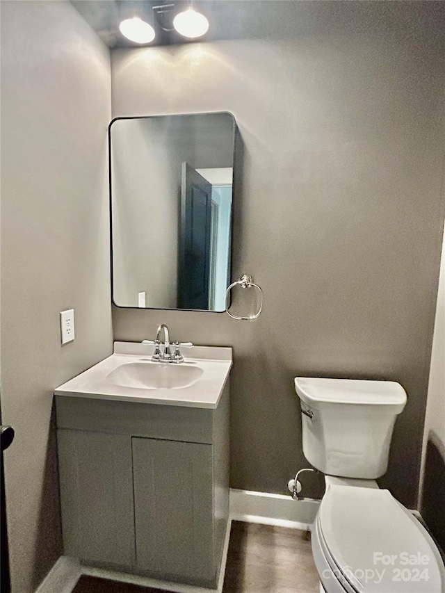 half bathroom featuring baseboards, vanity, and toilet