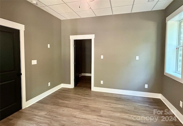 unfurnished room featuring a paneled ceiling, baseboards, and wood finished floors