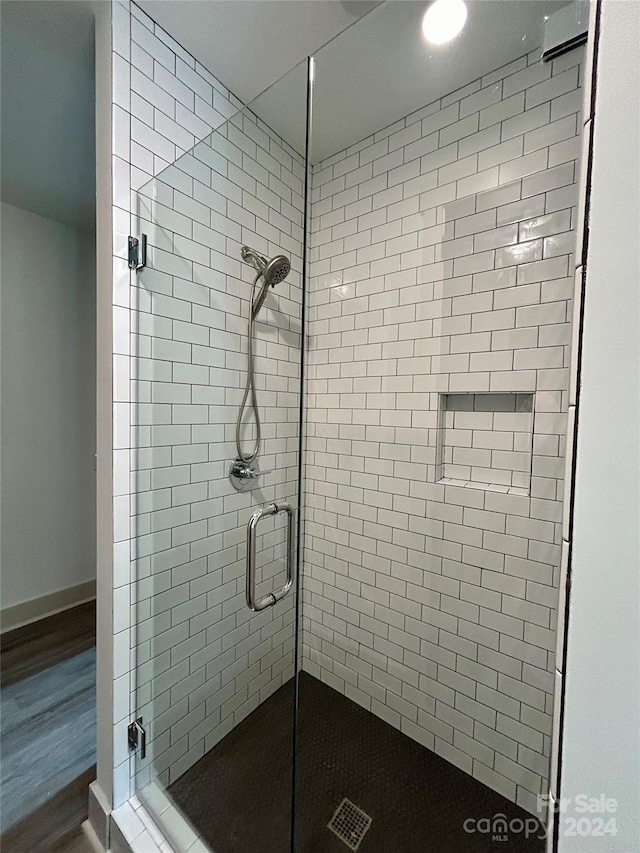 bathroom with a stall shower, baseboards, and wood finished floors