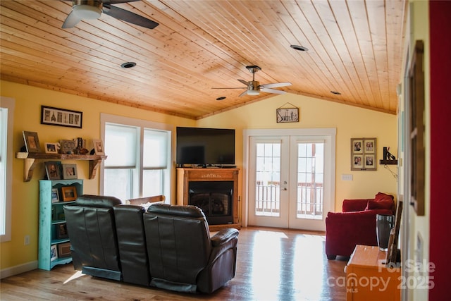 living area featuring french doors, a healthy amount of sunlight, vaulted ceiling, and wood finished floors