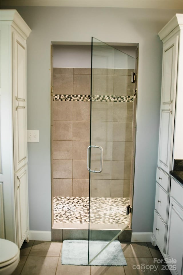 bathroom featuring vanity, a stall shower, tile patterned flooring, and toilet