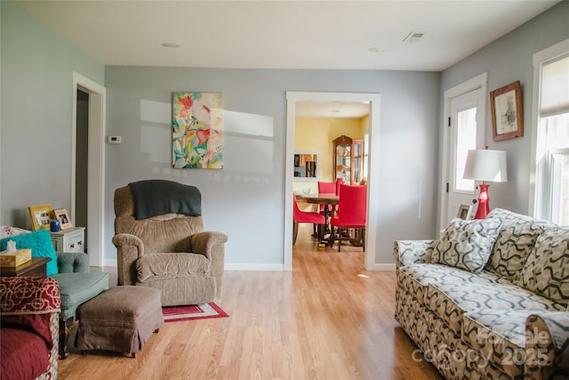 living area with baseboards, visible vents, and light wood finished floors