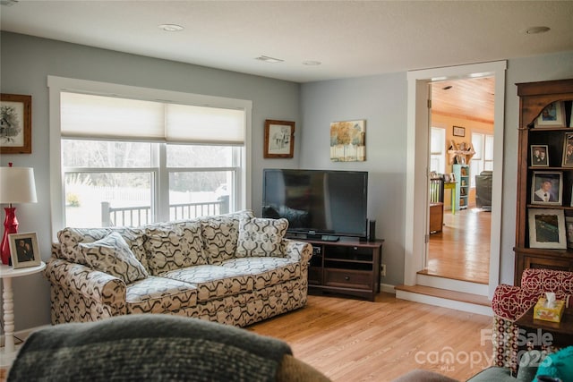 living room with baseboards, visible vents, and light wood finished floors