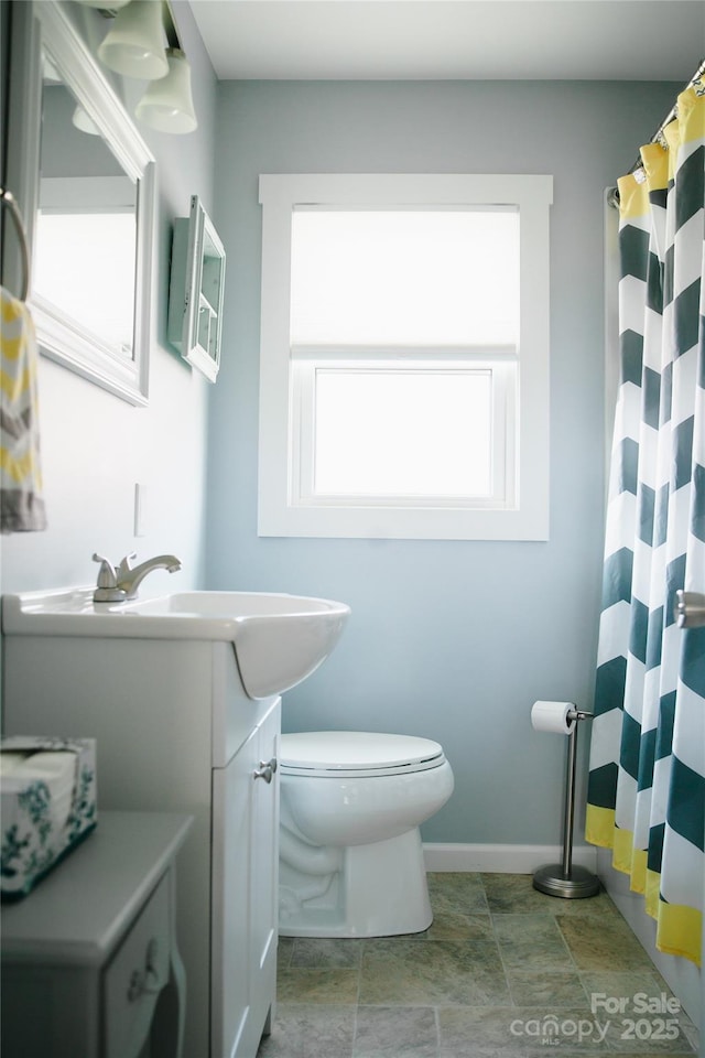 full bathroom with a shower with curtain, baseboards, vanity, and toilet