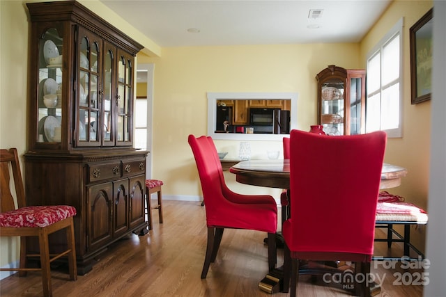 dining space with wood finished floors, visible vents, and baseboards