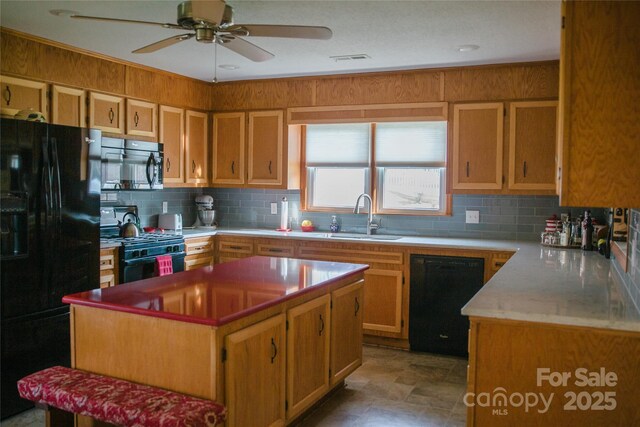 kitchen with a sink, visible vents, light countertops, decorative backsplash, and black appliances