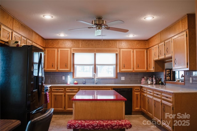 kitchen with a sink, light countertops, decorative backsplash, a center island, and black appliances