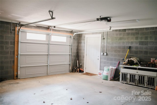 garage with concrete block wall and a garage door opener