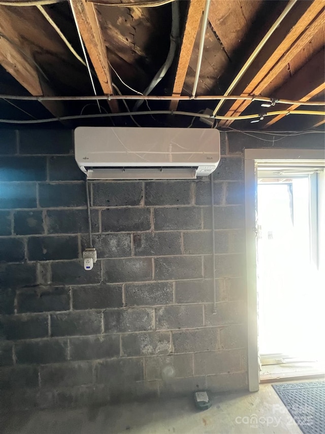 interior details featuring an AC wall unit, concrete block wall, and unfinished concrete floors