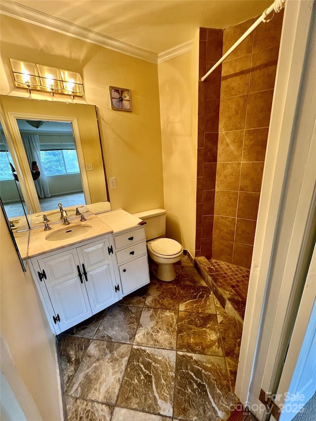 bathroom featuring toilet, ornamental molding, a tile shower, and vanity