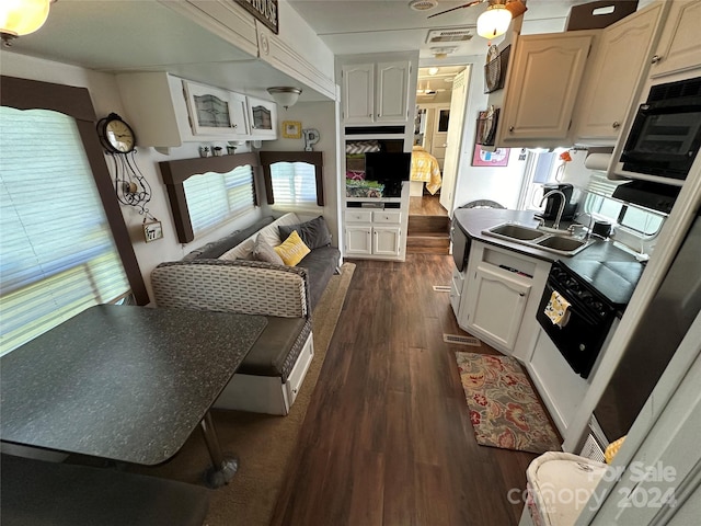 kitchen with ceiling fan, dark wood-type flooring, sink, dishwasher, and white cabinetry