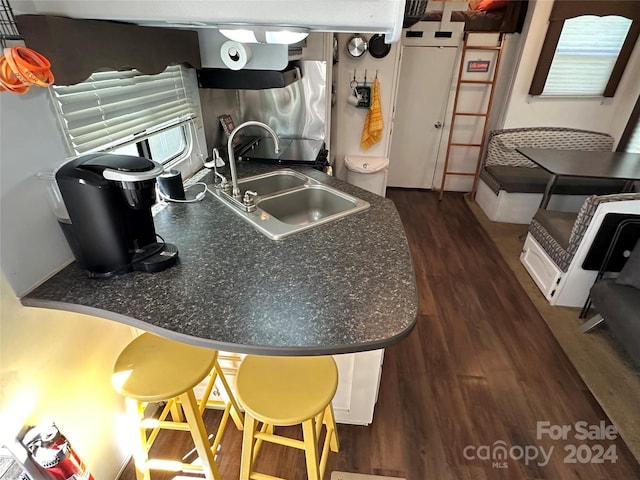 kitchen featuring a kitchen breakfast bar, sink, and dark wood-type flooring