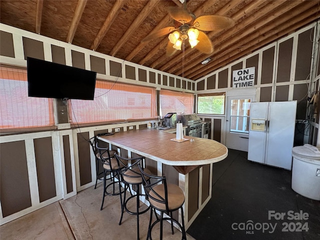 kitchen featuring tile countertops, ceiling fan, white fridge with ice dispenser, and lofted ceiling