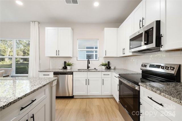 kitchen featuring appliances with stainless steel finishes, white cabinets, tasteful backsplash, and sink