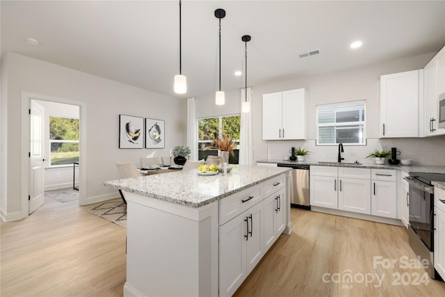 kitchen with a center island, sink, white cabinetry, light stone countertops, and stainless steel appliances