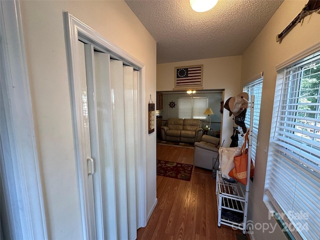 hallway with dark hardwood / wood-style floors and a textured ceiling