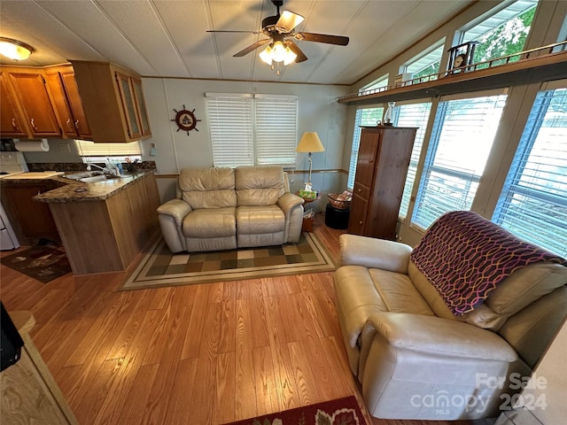 living room featuring lofted ceiling, ceiling fan, light wood-type flooring, and sink