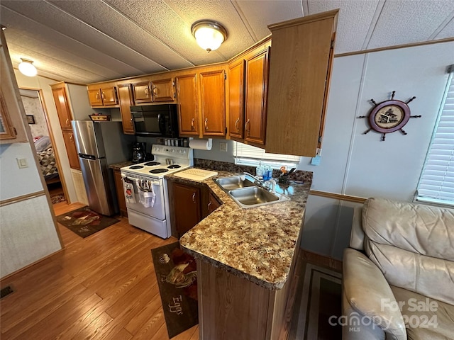 kitchen featuring stainless steel fridge, a textured ceiling, sink, light hardwood / wood-style flooring, and white electric stove