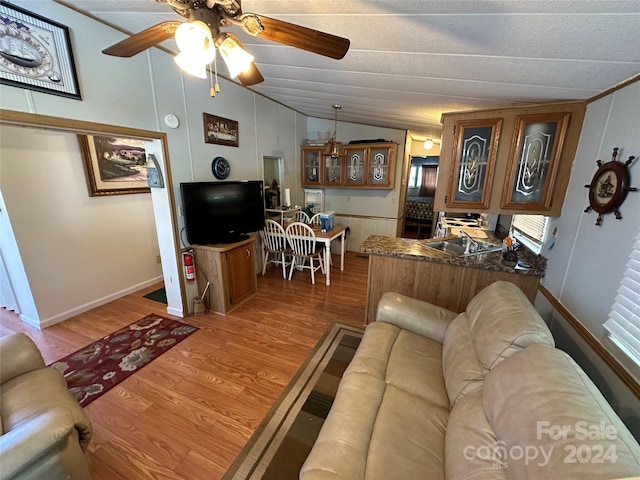 living room featuring a textured ceiling, ceiling fan, light hardwood / wood-style flooring, and lofted ceiling