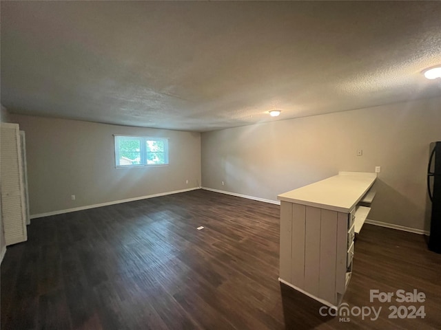 spare room featuring a textured ceiling and dark hardwood / wood-style floors