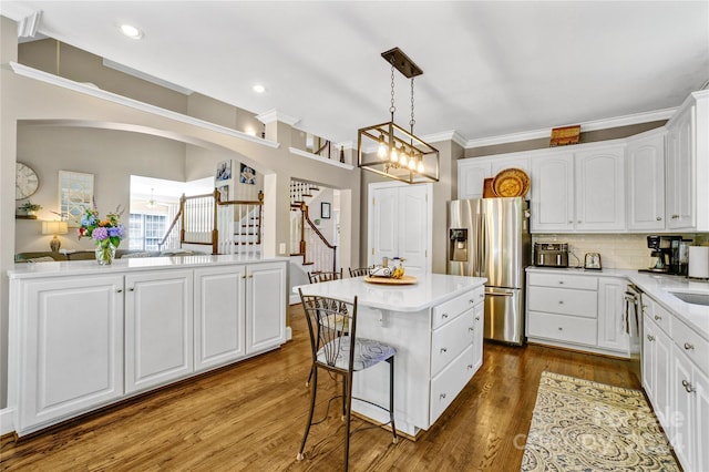 kitchen featuring a center island, tasteful backsplash, stainless steel fridge with ice dispenser, white cabinetry, and pendant lighting