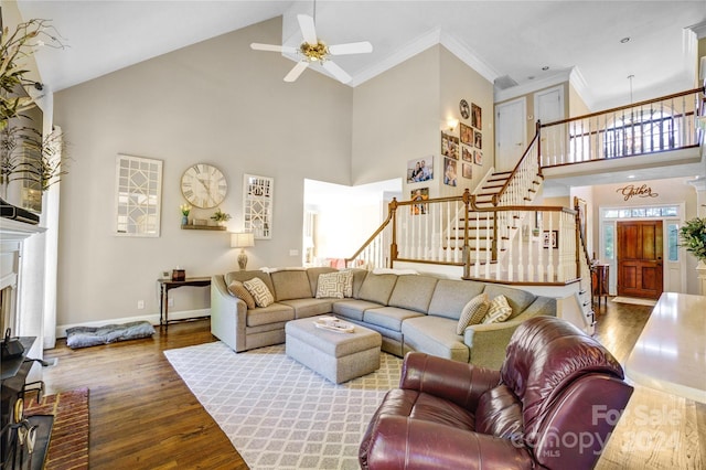 living room with wood-type flooring, a high ceiling, ceiling fan, and ornamental molding