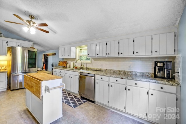 kitchen with white cabinets, appliances with stainless steel finishes, decorative backsplash, sink, and vaulted ceiling