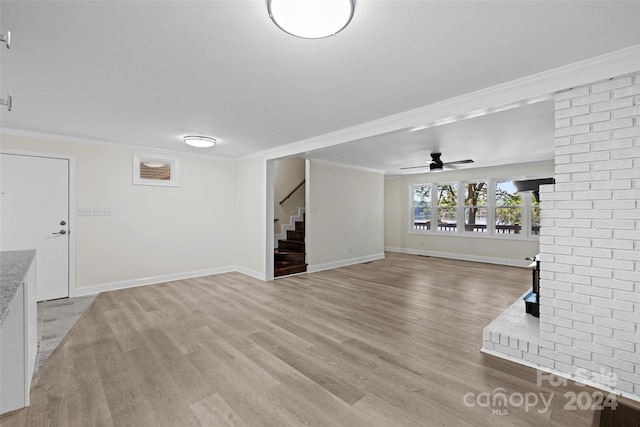 unfurnished living room featuring ceiling fan, light wood-type flooring, and ornamental molding