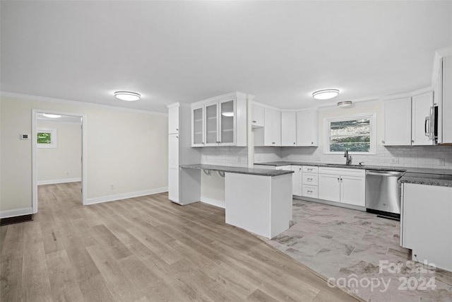 kitchen featuring appliances with stainless steel finishes, white cabinetry, dark stone countertops, sink, and a breakfast bar area