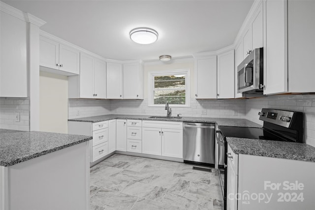 kitchen featuring white cabinetry, appliances with stainless steel finishes, backsplash, dark stone countertops, and sink