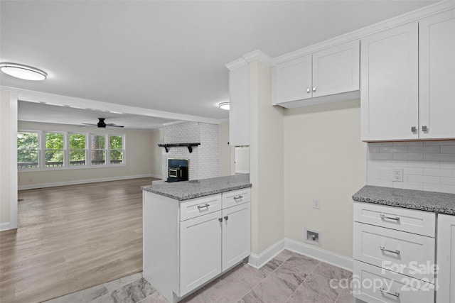 kitchen featuring tasteful backsplash, white cabinets, ceiling fan, and dark stone countertops