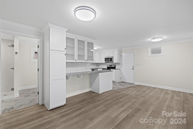 kitchen with white cabinetry, appliances with stainless steel finishes, light wood-type flooring, ornamental molding, and light stone counters