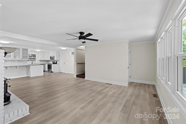 unfurnished living room featuring light wood-type flooring, ceiling fan, ornamental molding, and sink