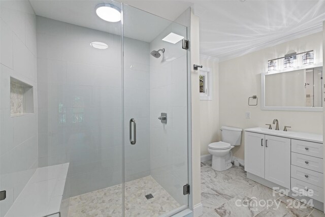 bathroom featuring a shower with shower door, vanity, and toilet