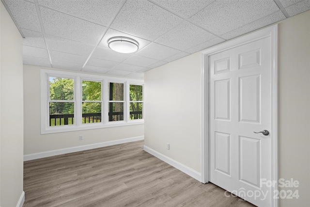 empty room with a paneled ceiling and light hardwood / wood-style flooring