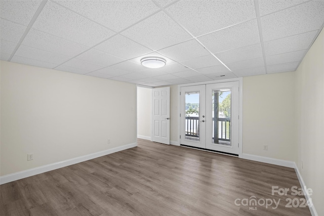 spare room with a drop ceiling, hardwood / wood-style floors, and french doors