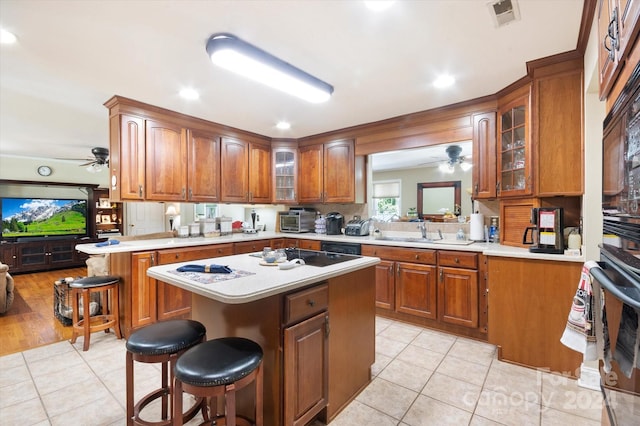 kitchen with light tile patterned flooring, kitchen peninsula, a kitchen bar, a kitchen island, and black appliances