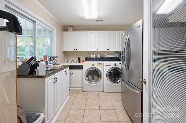 laundry area with cabinets, washing machine and dryer, crown molding, and light tile patterned flooring