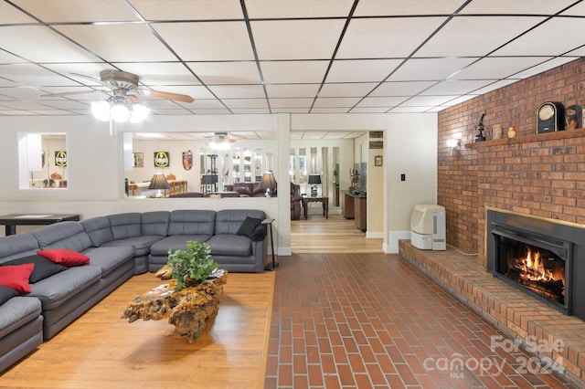 living room featuring a paneled ceiling and a brick fireplace