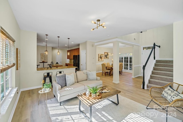 living room with light hardwood / wood-style floors, sink, and a chandelier