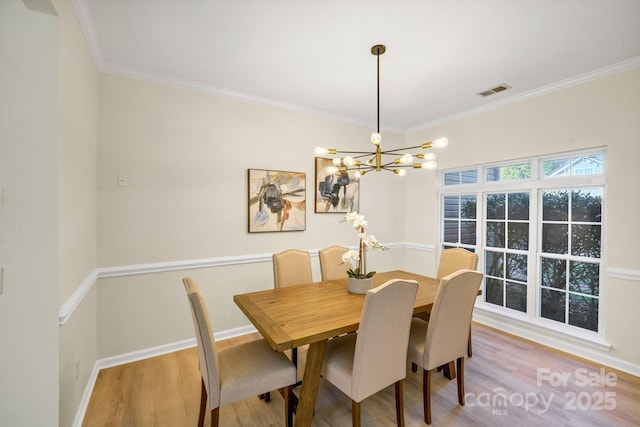 dining room with wood finished floors, visible vents, baseboards, an inviting chandelier, and crown molding