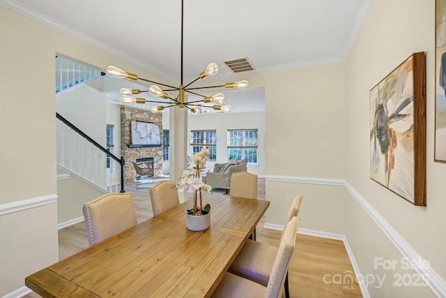 dining space featuring ornamental molding, a fireplace, wood finished floors, and visible vents