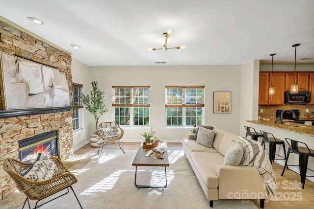 living room featuring light wood-style floors, visible vents, a fireplace, and baseboards