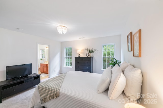 bedroom featuring light carpet, baseboards, visible vents, ensuite bathroom, and a notable chandelier