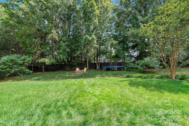 view of yard with a trampoline and fence