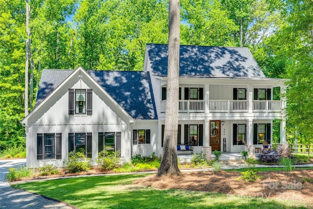 view of front of home featuring a balcony, a front lawn, and covered porch