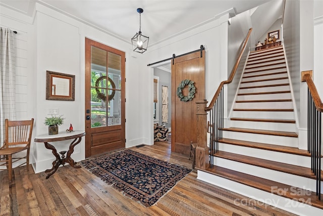 entryway featuring a barn door, ornamental molding, and hardwood / wood-style flooring