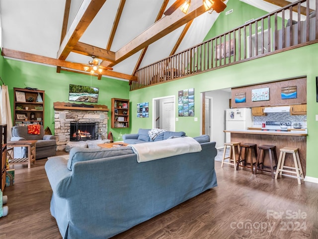 living room with ceiling fan, beam ceiling, dark wood-type flooring, a stone fireplace, and high vaulted ceiling