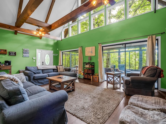 living room with beam ceiling, wood-type flooring, a high ceiling, and ceiling fan